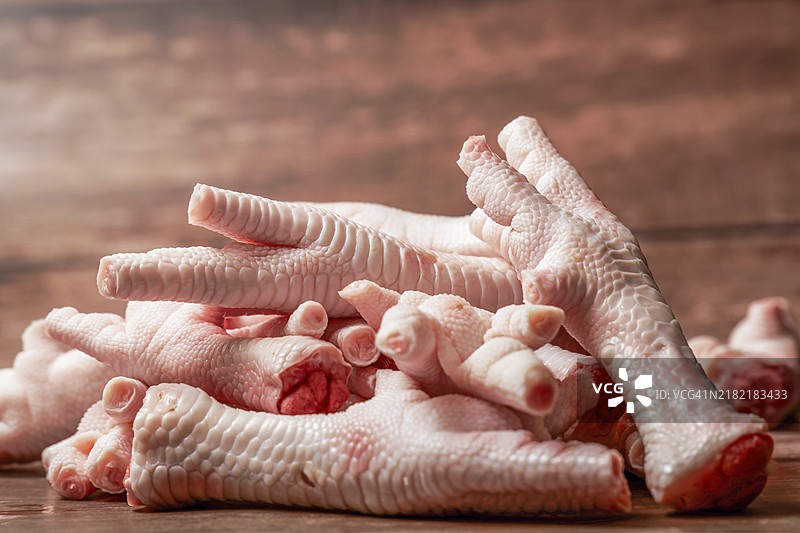 一堆干净的鸡爪放在木质背景上，留有空白空间。图片素材