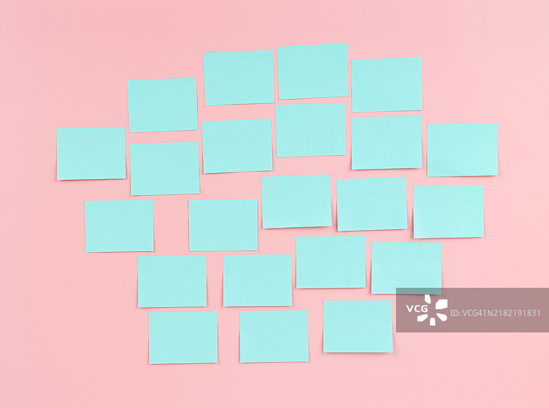 粉色墙壁上的空白蓝色便签纸。讨论商业、团队合作和头脑风暴的概念。图片素材