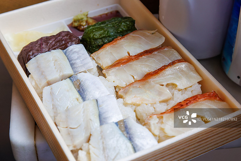 在火车上享用美味的烤红甘鲹和马鲛鱼押寿司便当（车站便当），还有罐装啤酒和罐装烧酒。图片素材