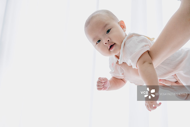 亚洲婴儿被母亲抱起；婴儿开心地笑着图片素材