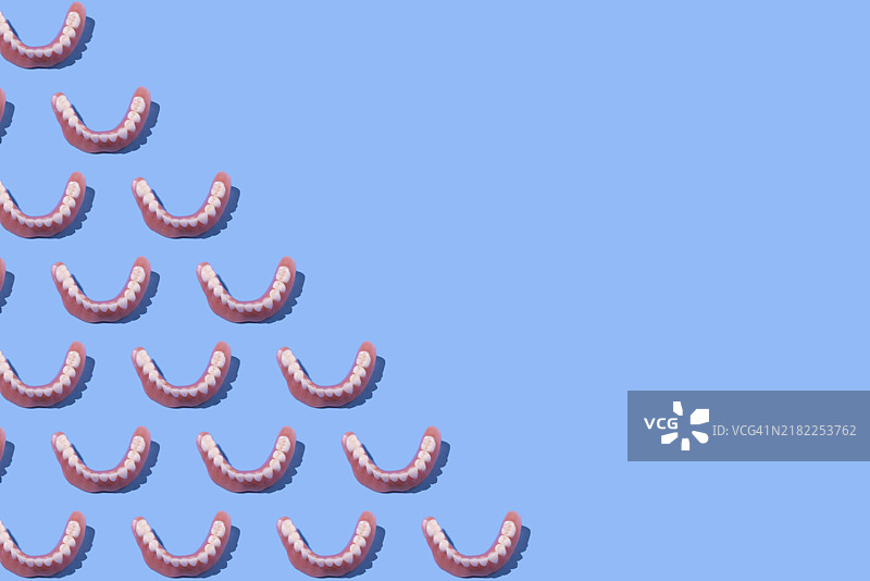 左侧的下颌义齿模型，蓝色背景。牙医，植牙，牙科，诊所和治疗。图片素材