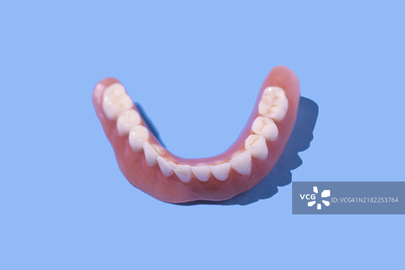 蓝色背景上的下牙托。牙医、植牙、牙科、诊所和治疗。图片素材