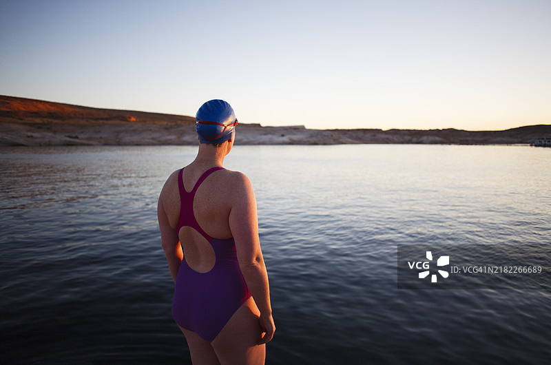 女性野泳者站在平静湖泊的水边图片素材