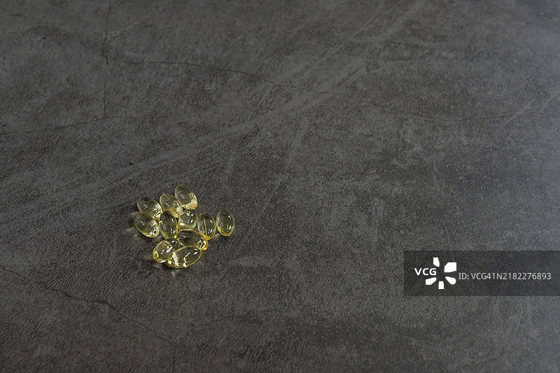 黑色纹理背景上的维生素D胶囊孤立展示图片素材