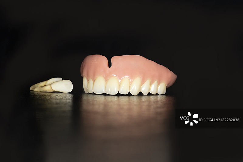 塑料制的上颚假牙，拔掉牙齿，黑色背景下的摄影作品图片素材