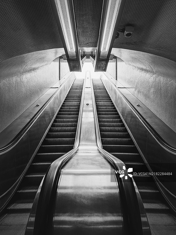 地铁自动扶梯的黑白建筑细节。对称的地下移动楼梯。图片素材