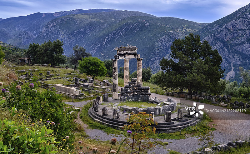 德尔菲,希腊,古希腊女神雅典娜·普罗奈亚的圆形神庙遗址。三根多立克柱子,圆形神庙的檐口上有浮雕,位于神圣的帕尔纳索斯山坡上,毗邻著名的德尔菲遗址。联合国教科文组织世界遗产地。广角俯拍。图片素材