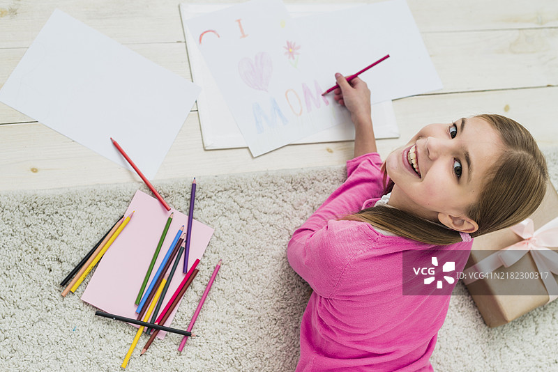 快乐的女孩在画“我爱妈妈”的纸张图片素材