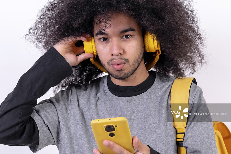 年轻男子在白色背景下，正在在线收听音乐流媒体。图片素材