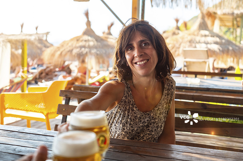 夏天海滩上的一对情侣举杯庆祝友谊，喝着几瓶啤酒图片素材