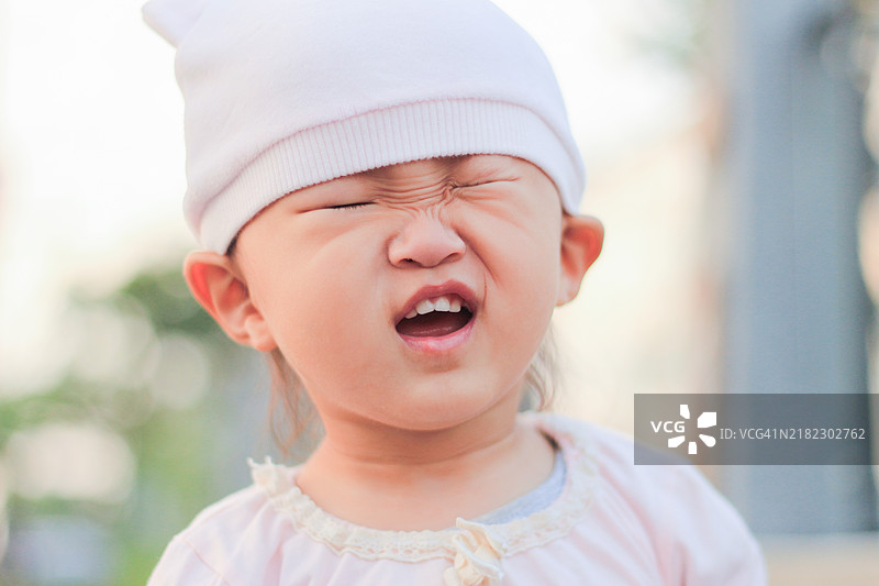 一个小亚洲女孩快要打喷嚏了，她皱着眉头。图片素材