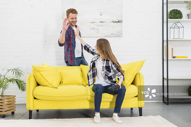 年轻情侣在玩电子游戏后互相击掌庆祝图片素材