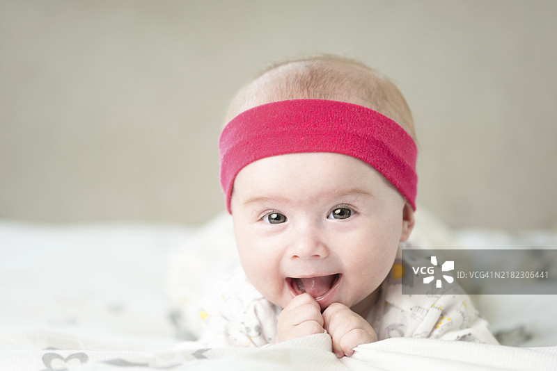 在明亮背景下微笑的可爱宝宝肖像。新生儿概念图片素材