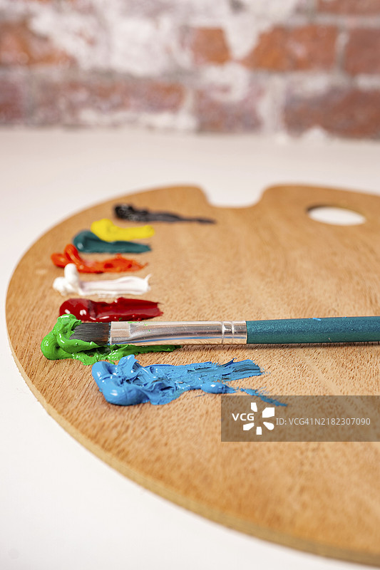 白色背景上的木质调色板，配有彩色油漆和画笔图片素材