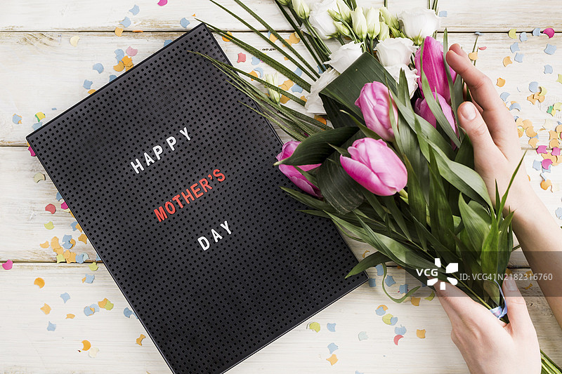 母亲节快乐的标题牌，手持花束的人图片素材