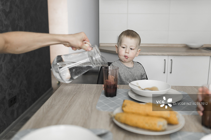 男孩模样的人在早餐时倒水入杯中图片素材