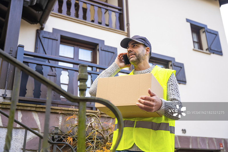 一位年轻的快递员穿着保护制服，提供送货客户服务。图片素材