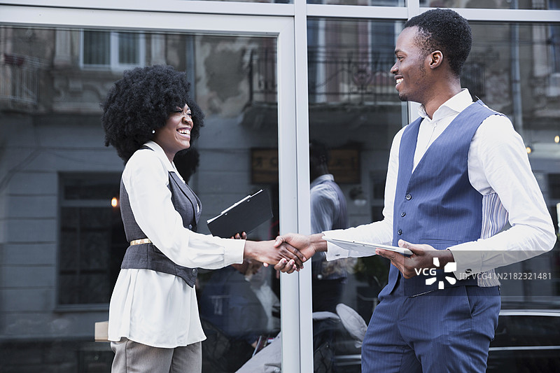 年轻的非洲商人在玻璃窗前握手图片素材