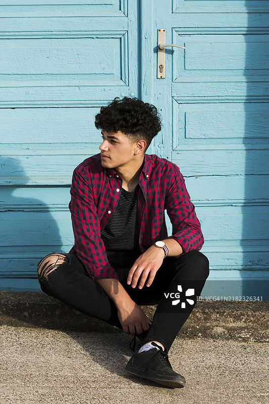 坐在路边的穿着格子衬衫的少数民族青少年图片素材