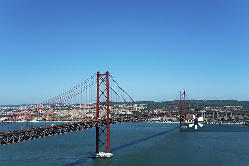 红色悬索桥俯瞰河流,周围是城市景观,25号四月桥,悬索桥横跨塔霍河,双层桥,公路交通和铁路交通,里斯本,葡萄牙,欧洲图片素材