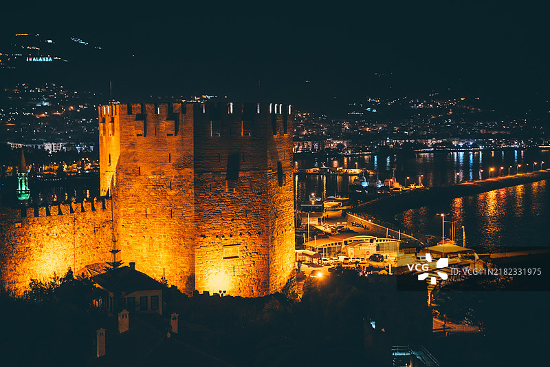 安塔利亚土耳其阿拉尼亚堡垒的红塔和古老城墙在夜晚的景象。图片素材