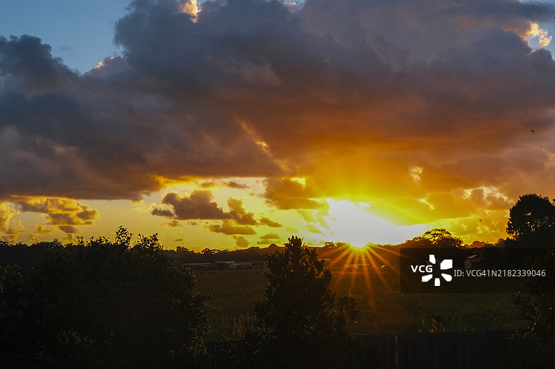 金色日出映照山丘，天空呈现出戏剧性的景观图片素材