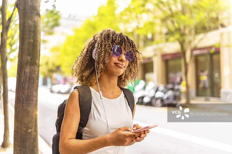 侧面特写，留有空白的拉丁裔快乐女性在街上用手机听音乐图片素材