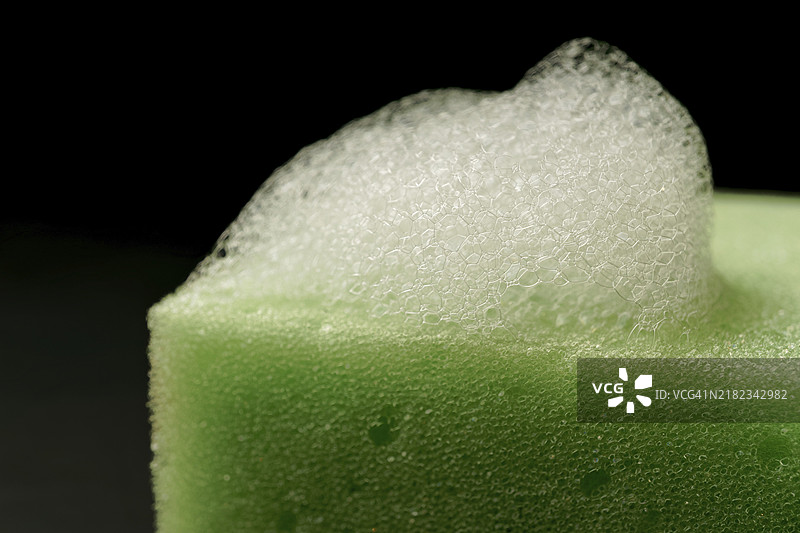 黑色背景上孤立的绿色海绵上的泡沫和留白图片素材