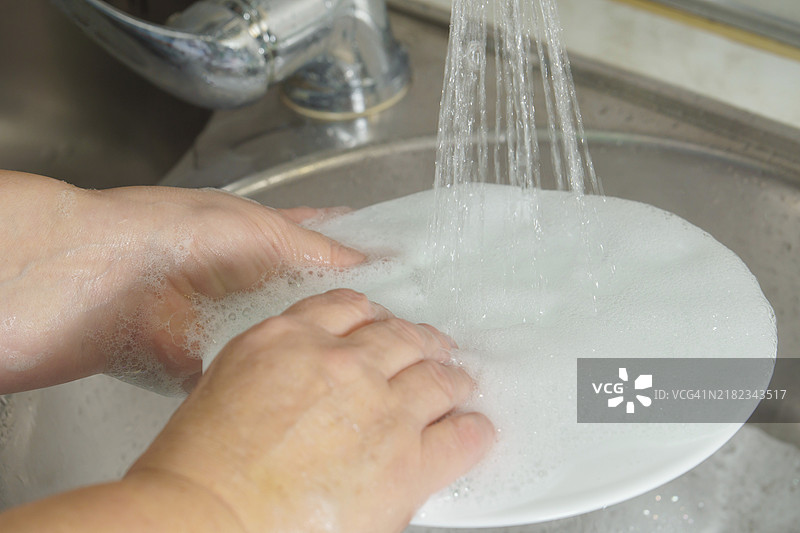女人在厨房水槽里洗碗，特写镜头。清洁家务图片素材