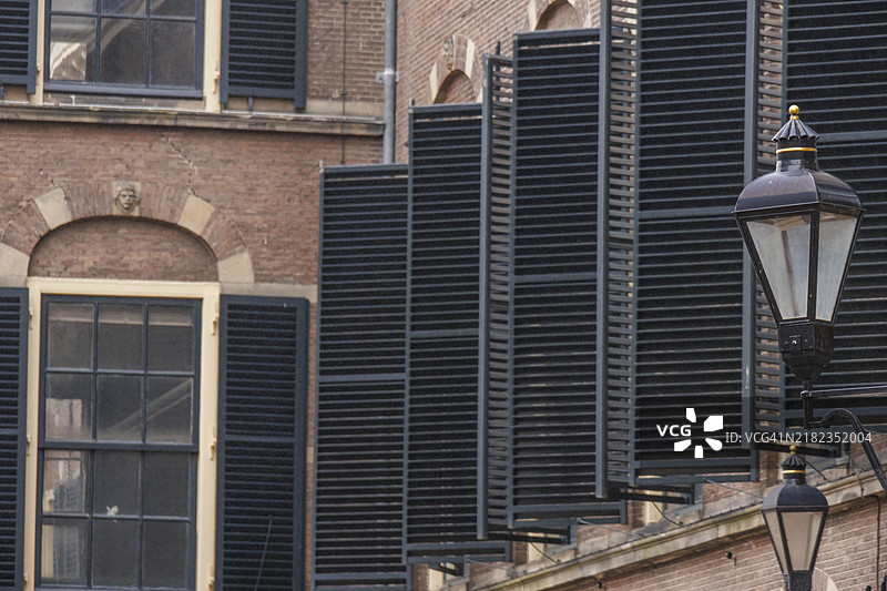 荷兰海牙一座砖砌建筑的正面，配有小百叶窗和一盏古老的灯。图片素材