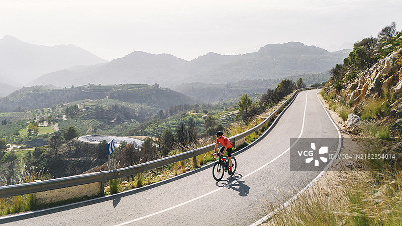 西班牙山区一位成熟骑行者的景象，秋日阳光明媚却略显朦胧。图片素材