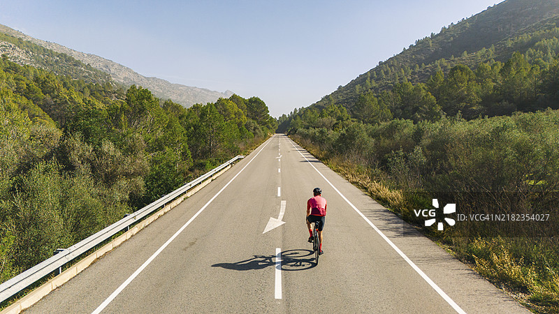 西班牙山区直路上骑自行车者的无人机/高空视角图片素材