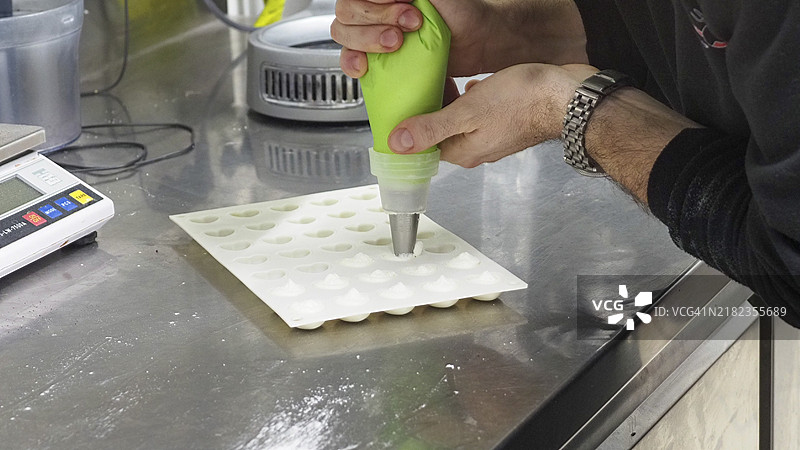 厨师在专业厨房中将奶油挤入硅胶烘焙模具上图片素材