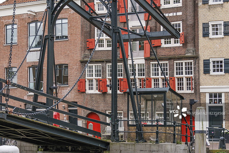 装饰精美的桥梁位于住宅建筑前，明亮的红色百叶窗和门，荷兰多德雷赫特。图片素材