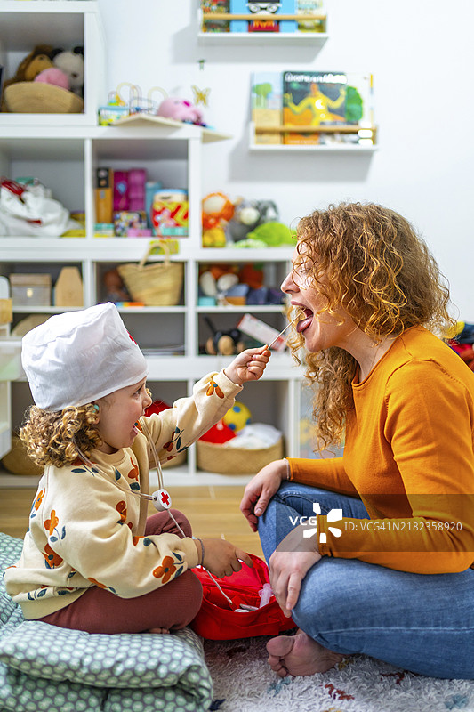 可爱的白人女孩在检查她母亲的舌头，玩护士的游戏。图片素材