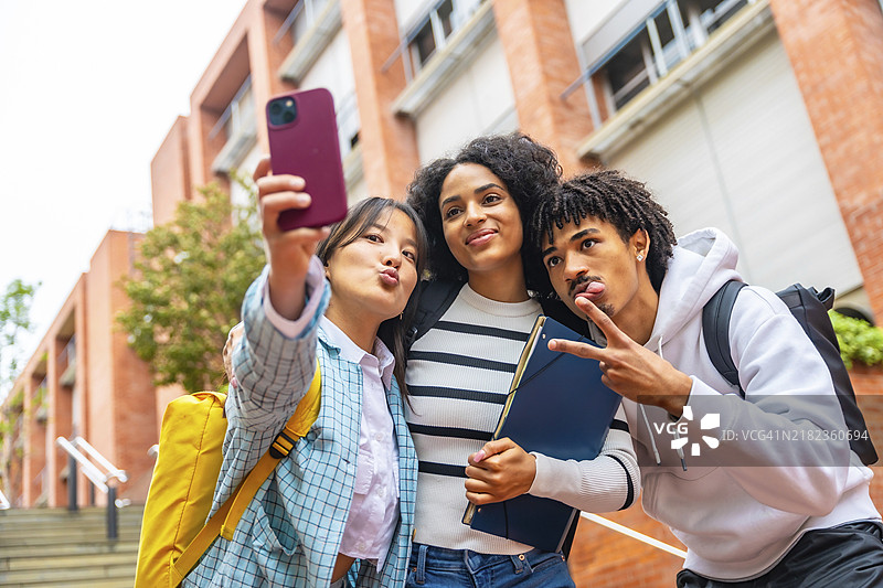 低角度视图的三位快乐的多种族大学生在校园外自拍的肖像图片素材