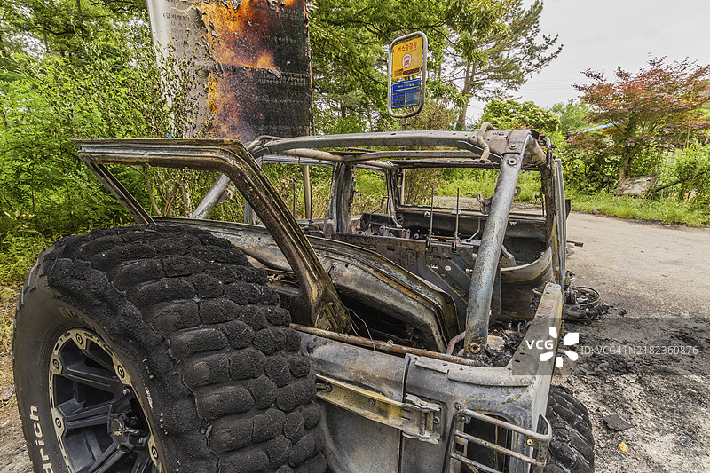 被火焚毁的汽车后视图，停在韩国乡间公路旁。图片素材