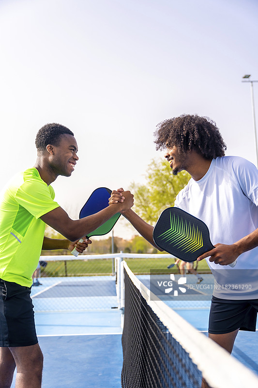 两个非洲运动员在打皮克球前握手的侧面垂直视图图片素材