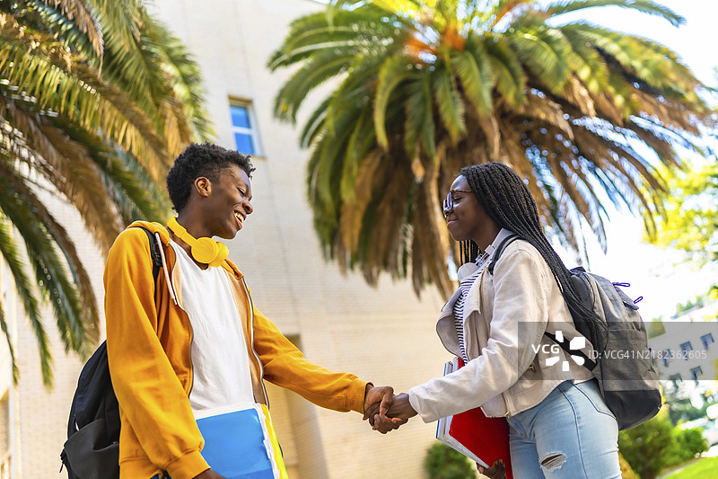 两位年轻时尚的非洲大学生在大学外侧面握手图片素材