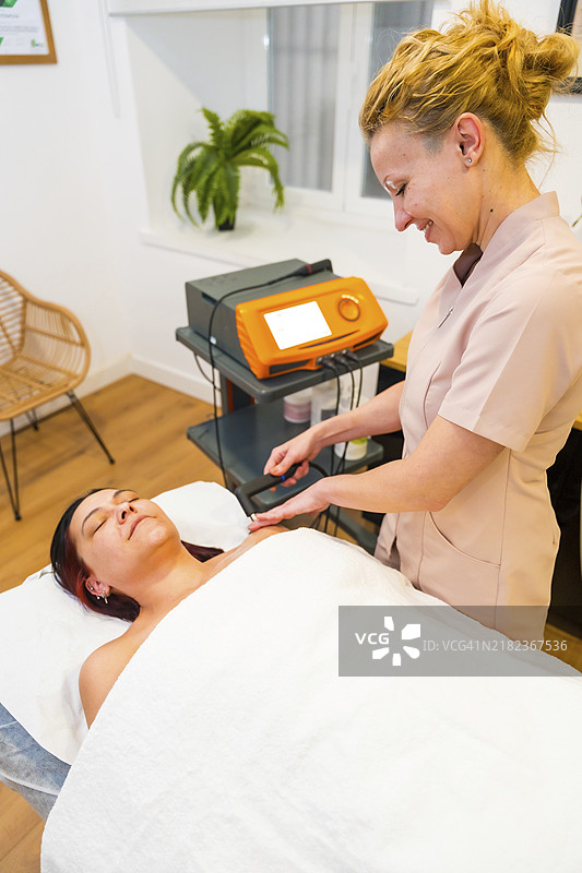 友好的女性物理治疗师使用Indiba技术为患者治疗疼痛的竖版照片图片素材