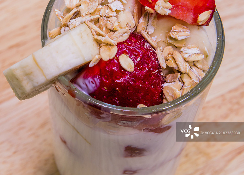 草莓、香蕉和燕麦放在酸奶杯中。健康的早餐或甜点。图片素材