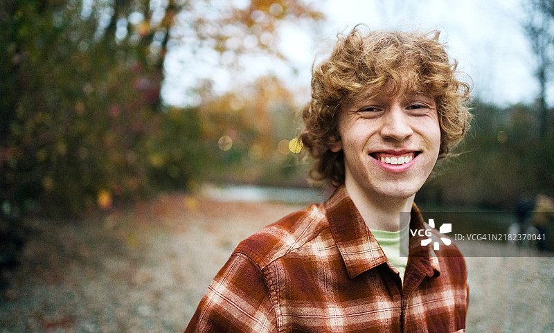 在徒步旅行时，站在河边的年轻男子笑着图片素材
