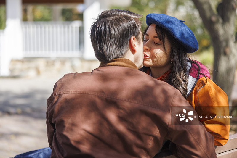 在郊区公园分享亲密时刻。拉丁裔情侣在长椅上享受亲密的瞬间。图片素材