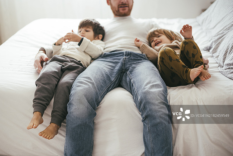 顽皮的父亲与儿子们在床上玩耍图片素材
