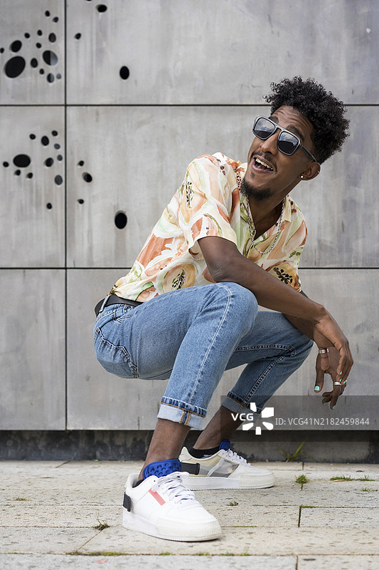 城市非洲裔男子在户外蹲下摆姿势的竖版肖像图片素材