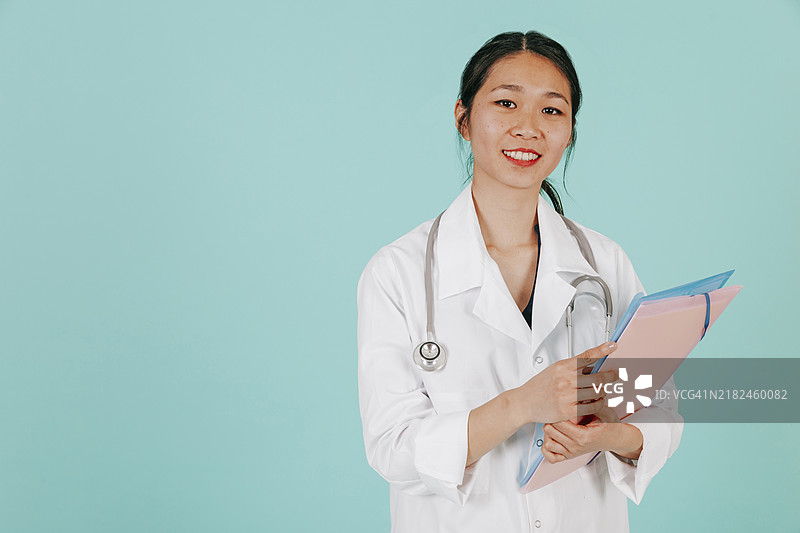 微笑的亚洲医生手持听诊器和文件夹图片素材