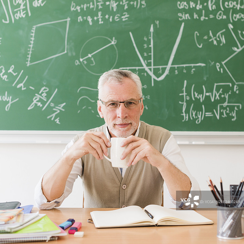 微笑的老师在教室里喝饮料图片素材