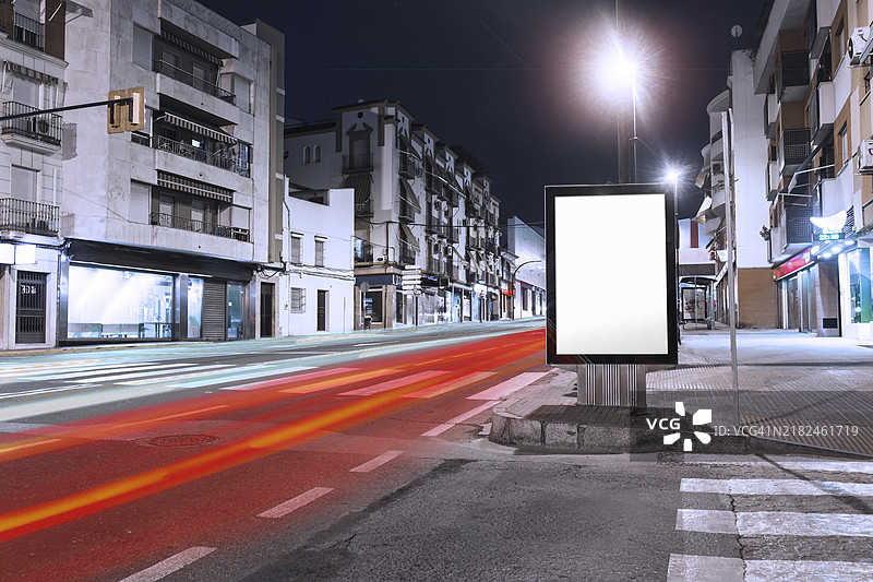 城市人行道上空白广告牌旁的汽车光轨。美丽的照片。图片素材