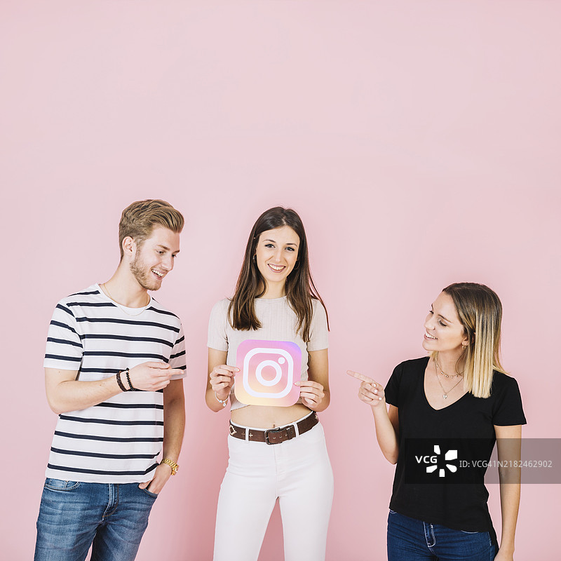 快乐的男女指着他们的朋友，朋友手持Instagram图标图片素材
