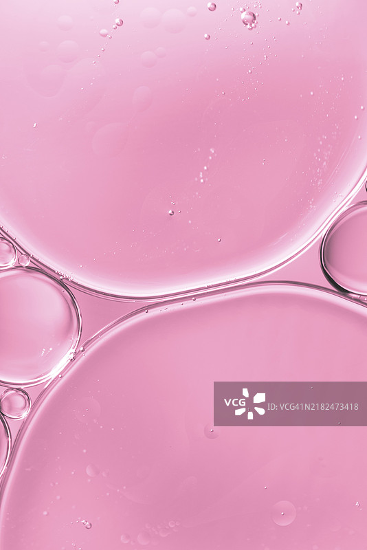 半透明的油滴与水，柔和的粉色模糊背景图片素材